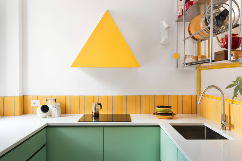 A yellow and green kitchen with a triangle on the wall.