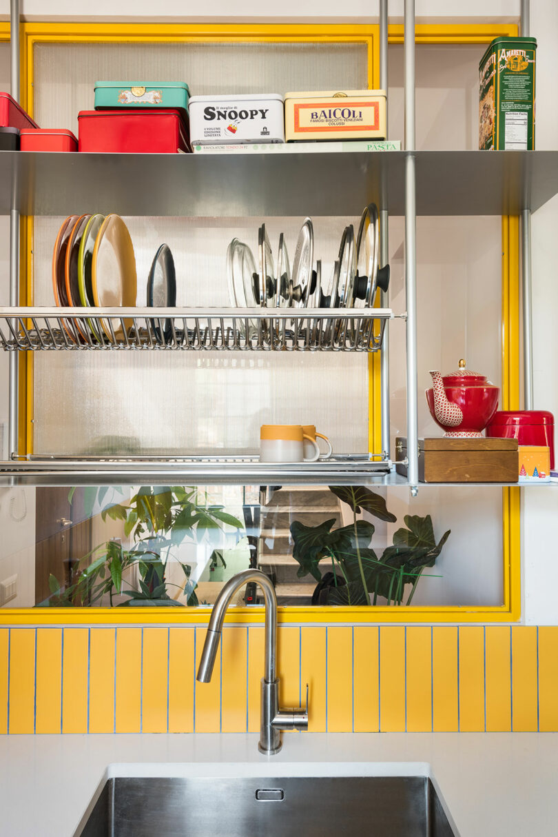 A yellow kitchen with a sink and shelves.