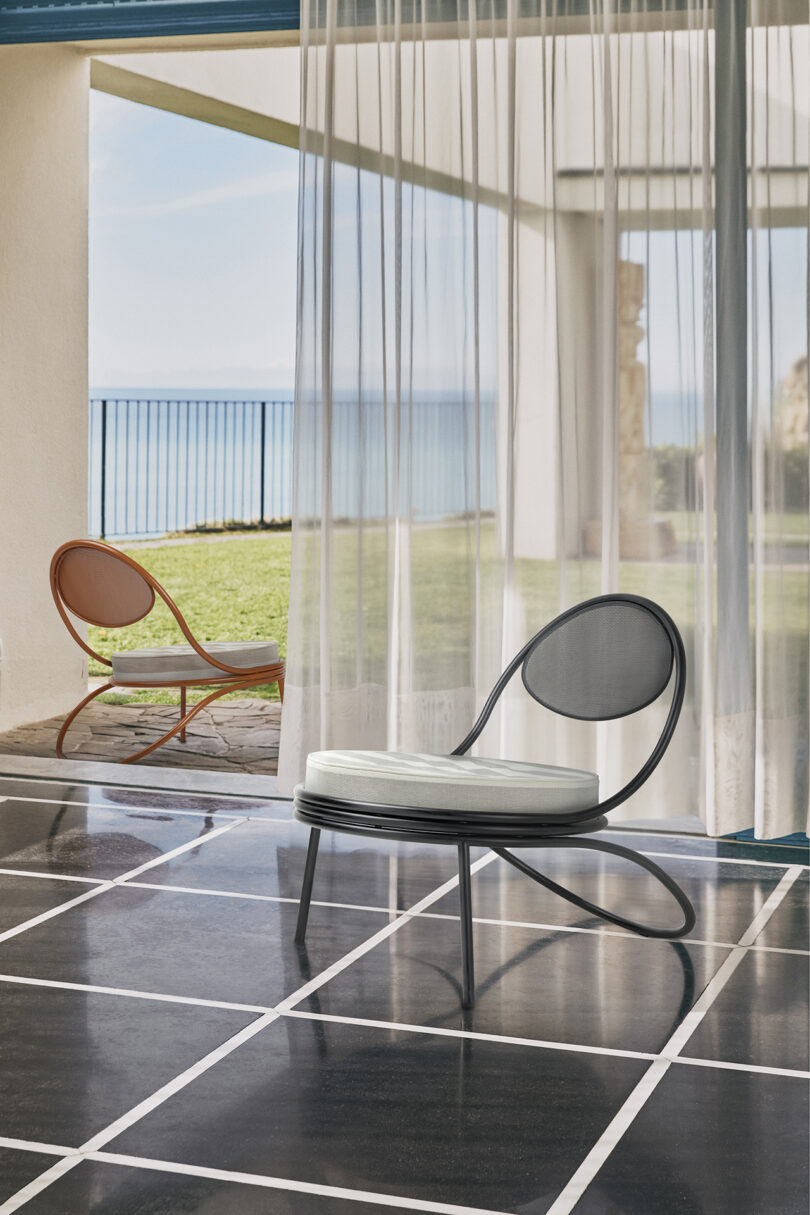 Two lounge chairs in a room with a view of the ocean.