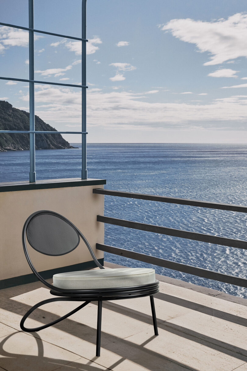 A lounge chair on a balcony overlooking the ocean.