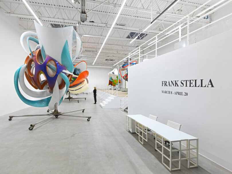 An art exhibition featuring abstract sculptures by frank stella, with a visitor observing the artwork.