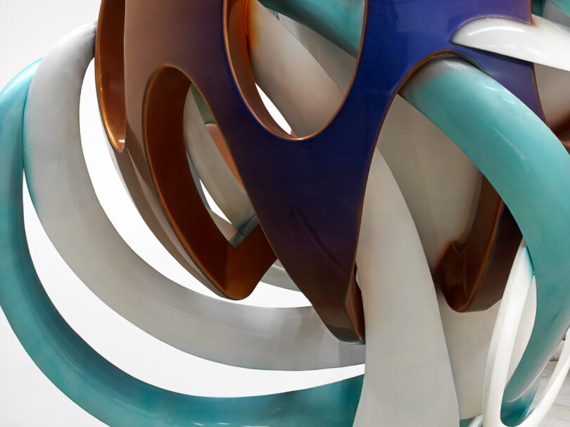 Abstract interlocking sculpture with cool-toned hues.