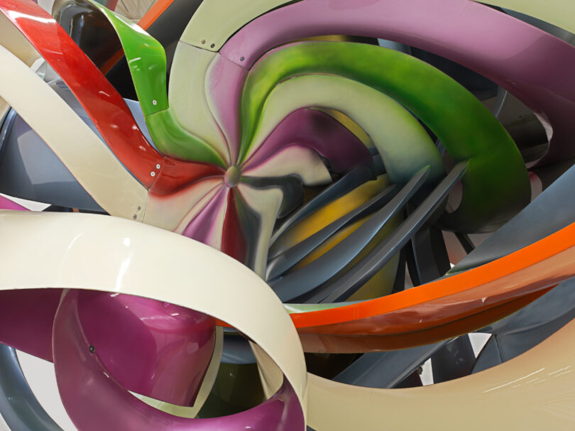 Colorful close-up of an aircraft engine turbine blades.