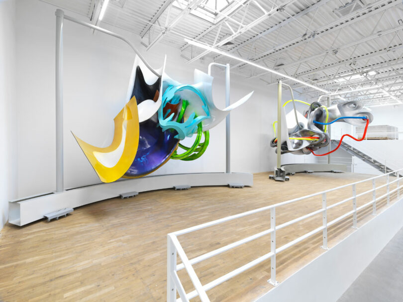 A modern art gallery displaying large, abstract wall sculptures in a bright, well-lit space.