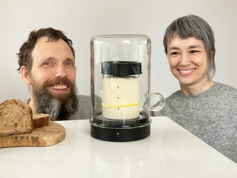 two people standing eye level with a jar of sourdough bread starter