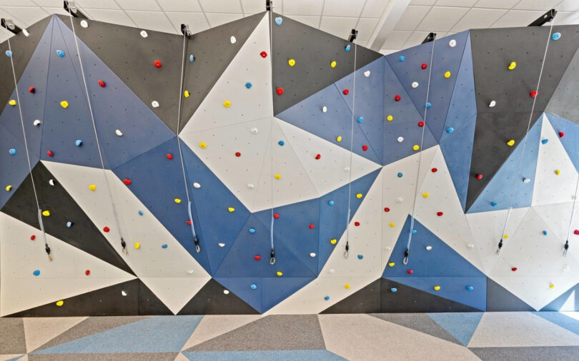 climbing wall covered in recycled black, blue, and grey recycled rubber flooring