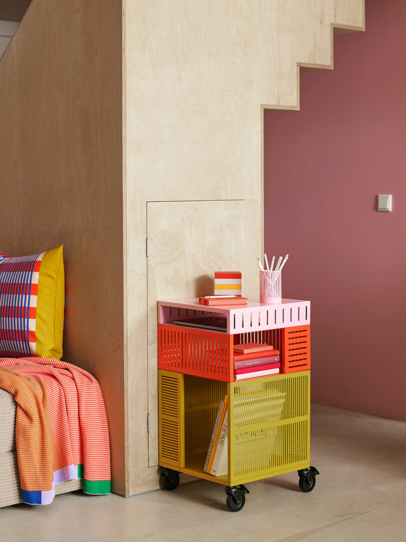 angled shot of multi-color metal cart against a wall with portion of colorful bedding to side