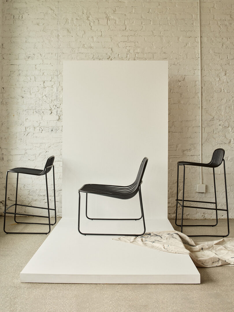 Três cadeiras pretas contemporâneas com design minimalista em uma sala iluminada.