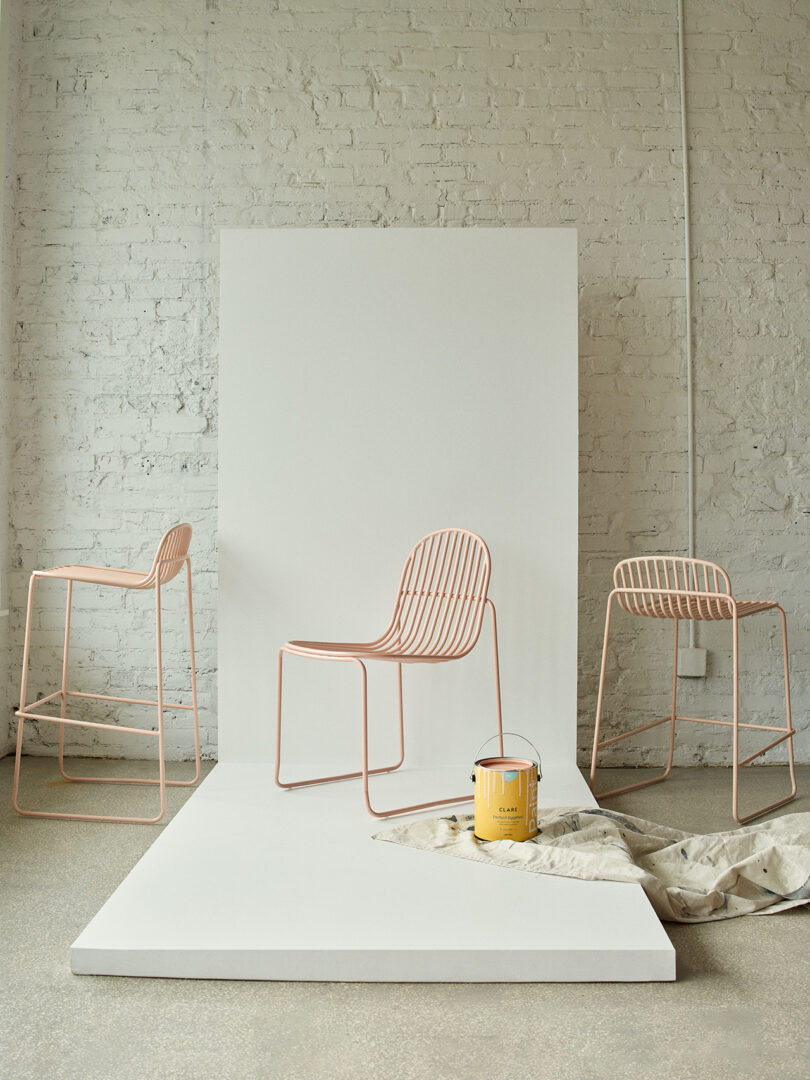 Três cadeiras contemporâneas rosa claro com design minimalista em uma sala iluminada.