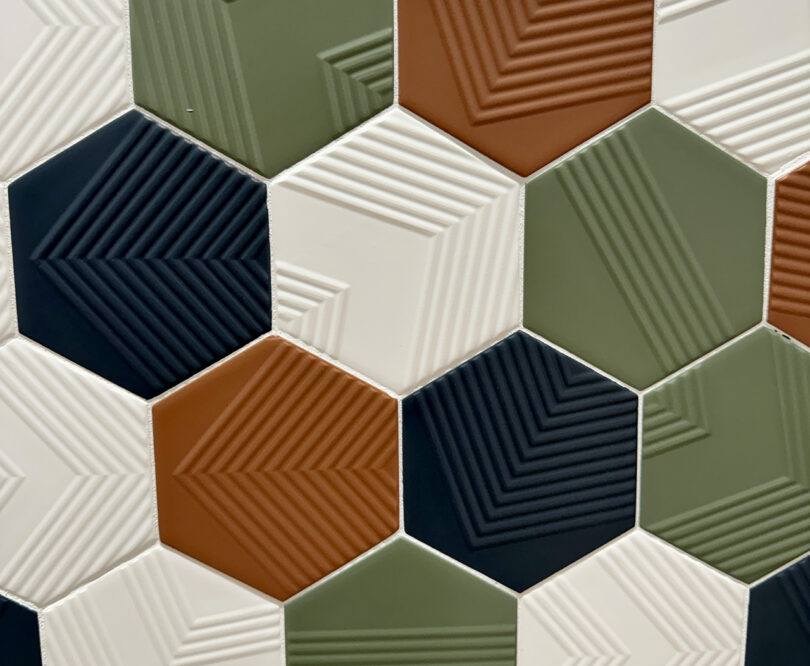 A close up of a glazed and textured color hexagonal tiles.