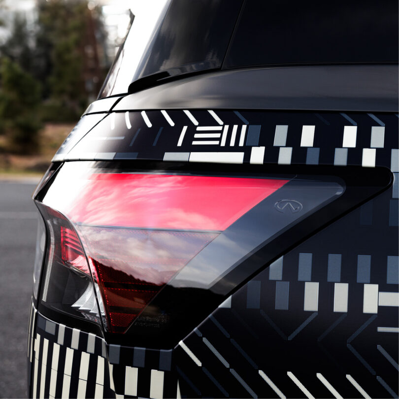 Rear light left corner section of the new Infiniti GX80 wrapped in a monochromatic dash and square pattern designed by digital artist Kaoru Tanaka