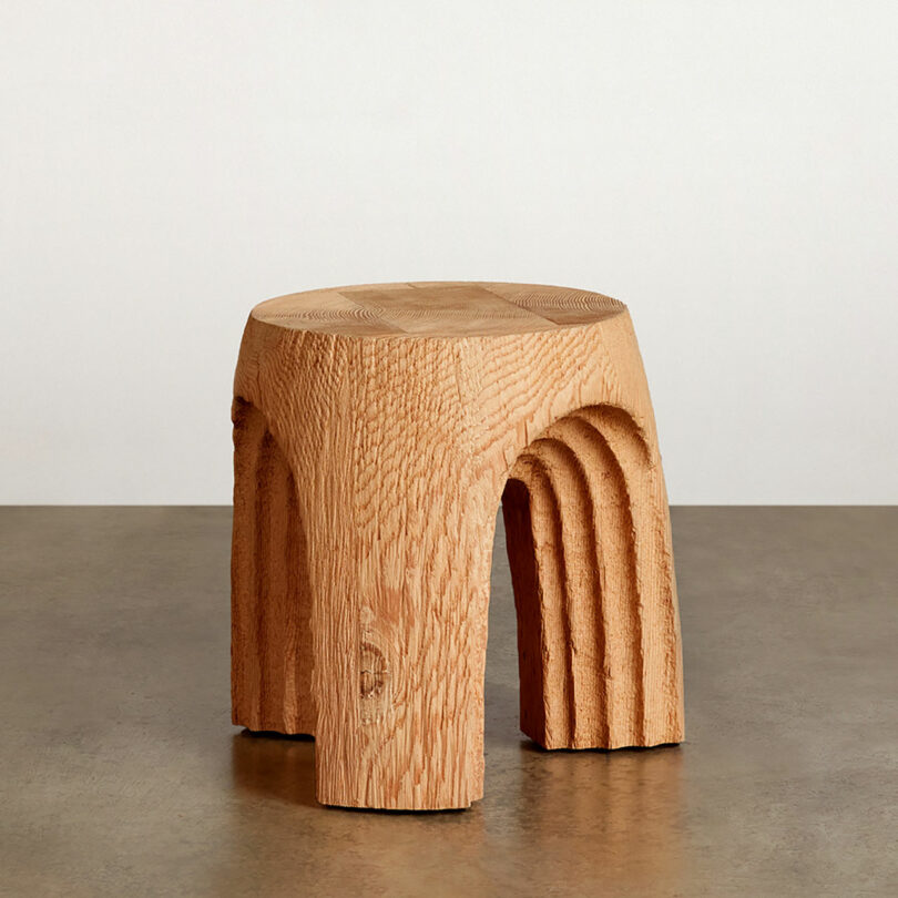 Wooden stool with arched leg design on a plain background.