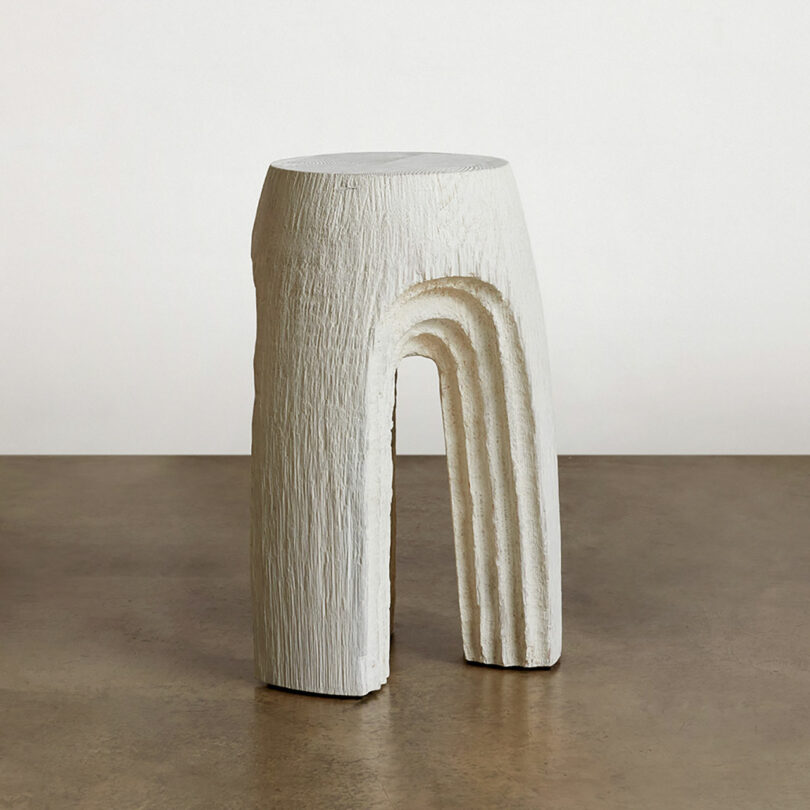 Sculptural white stool with an arched base on a simple background.