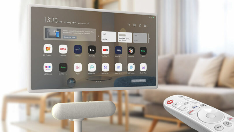 LG StanbyME Speaker and Rollable Display with various entertainment app icons on the screen, accompanied by a voice remote control, located in a modern living room.