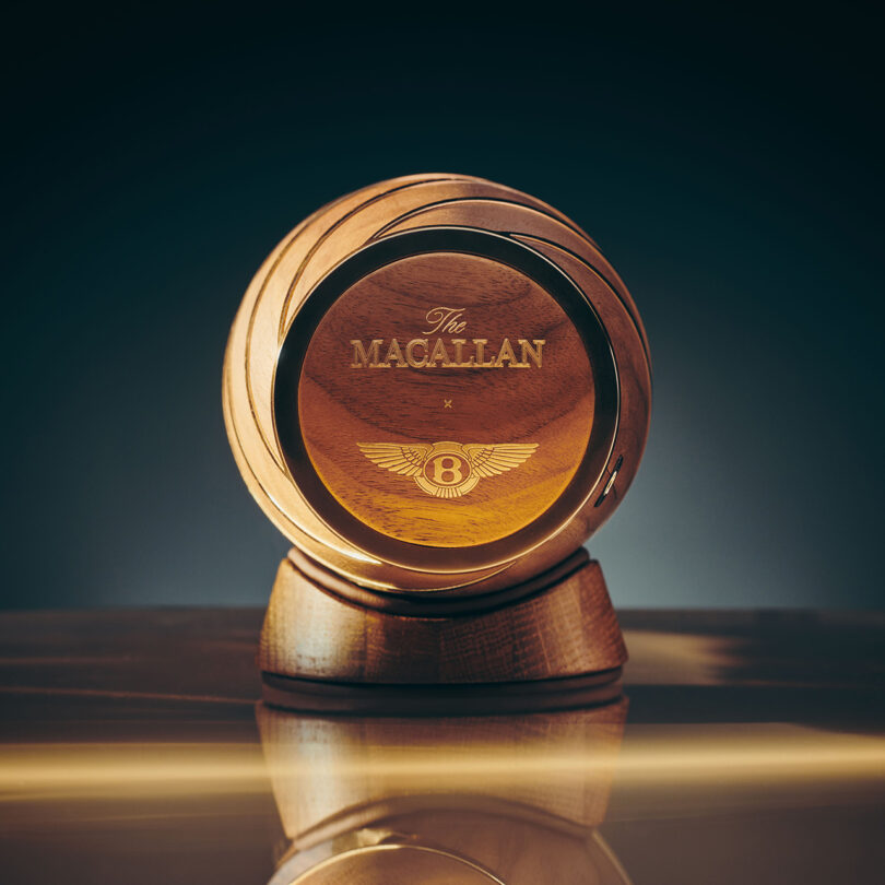 A bottle of The Macallan Horizon whiskey vessel on a reflective surface with a warm background glow.
