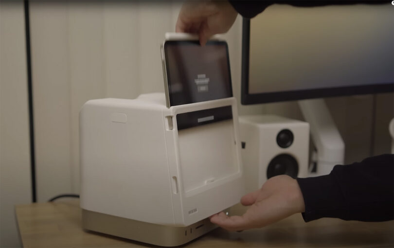 Person placing an iPad mini into a small white 3D printed Macintosh Studio dock