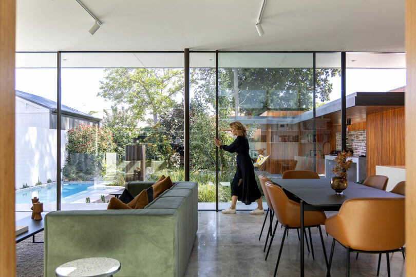 A woman is standing in front of a glass door in a modern home.