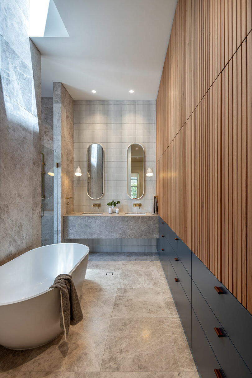 A modern bathroom with wooden cabinets and a bathtub.