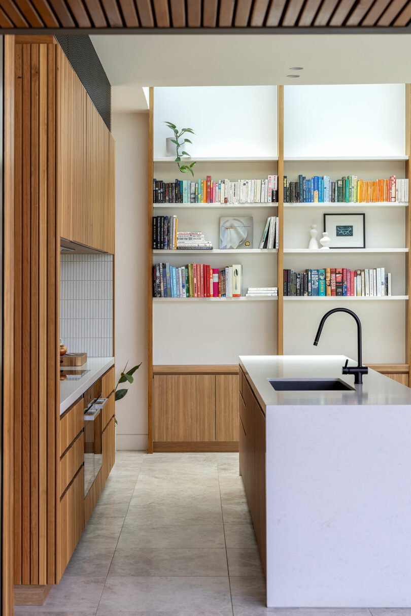A modern kitchen with a wooden island and bookshelves.