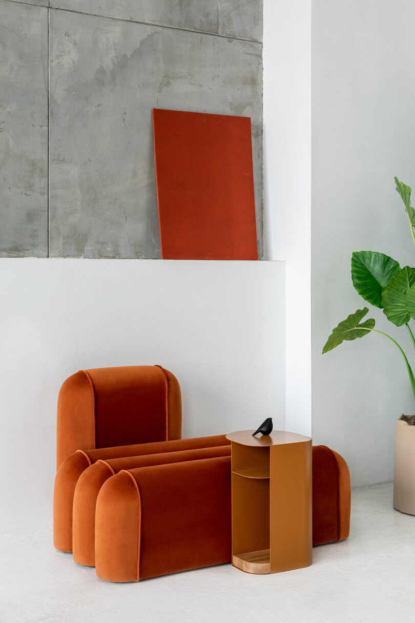 Burnt orange sofa, a side table, and a plant.