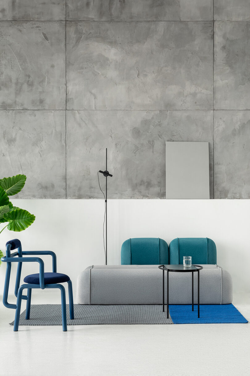 Modern living space with a grey and blue sofa, abstract chair, and minimalist decor.