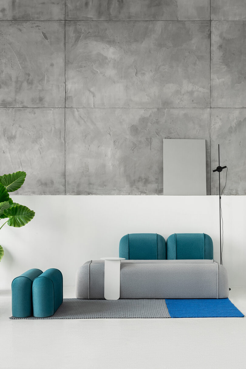 Modern living space with a grey and blue sofa, coordinating stool, and side table.