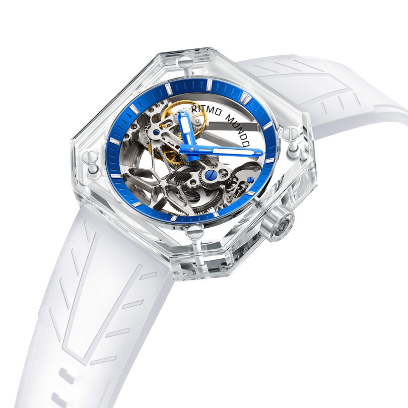 Luxury Ritmo Mundo Pegasus Watch with a transparent case and white strap and blue metal ring dial.