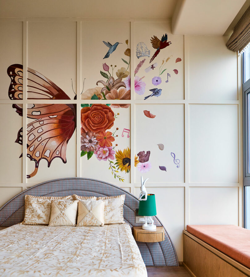 یک اتاق خواب با یک پروانه بزرگ و نقاشی دیواری گلدار بالای سر تخت.