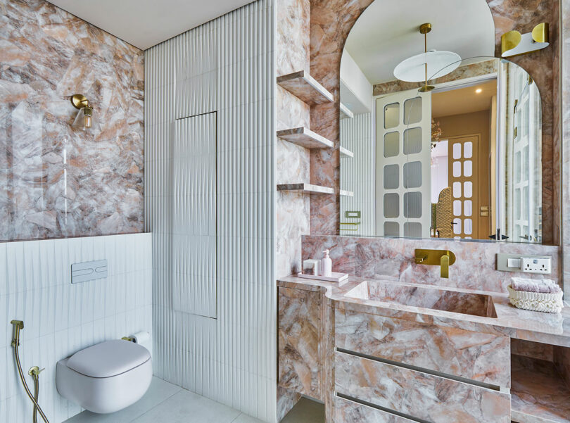 Modern bathroom with pink marble finishes and contemporary fixtures.
