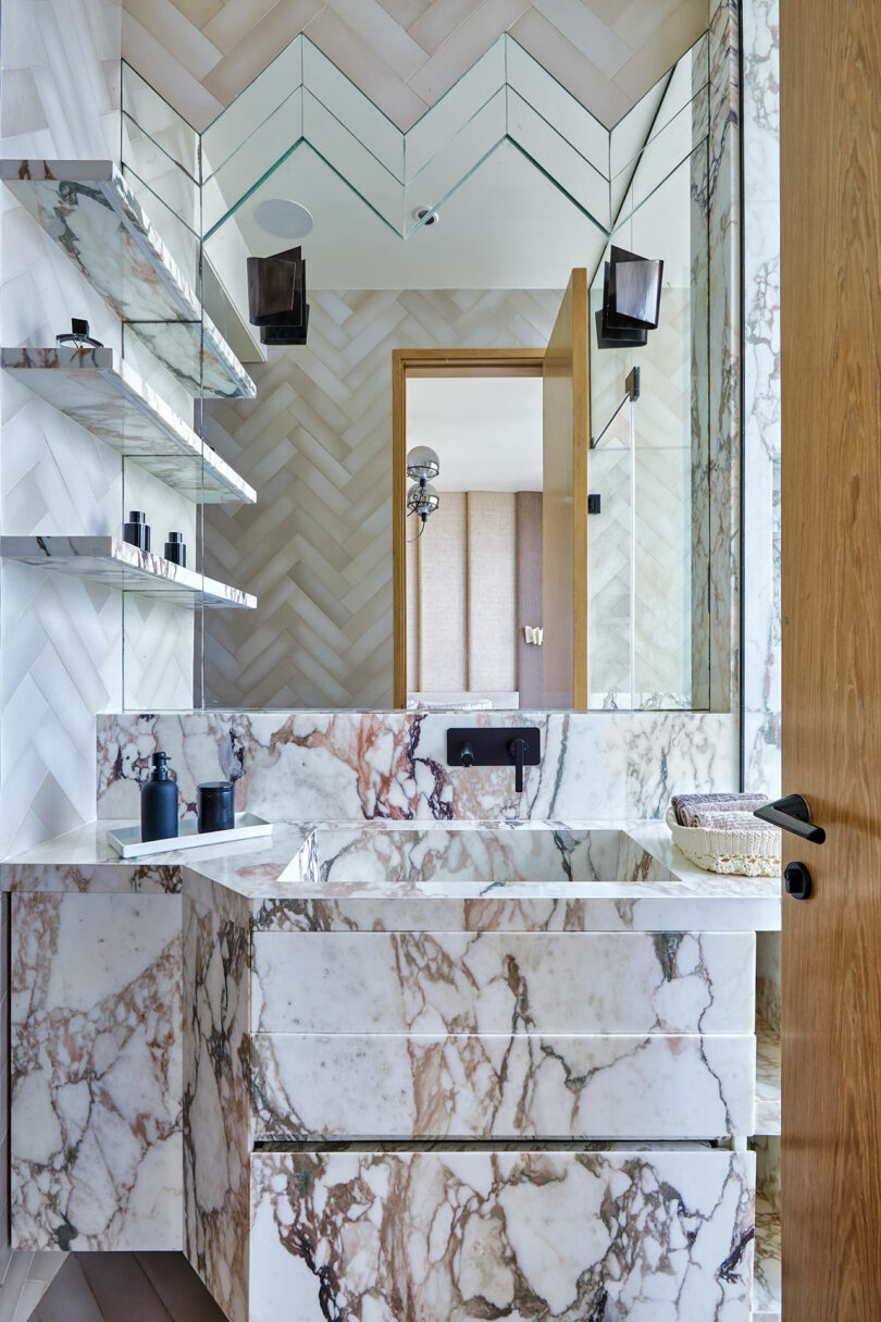 Modern bathroom design with marble finishes and herringbone tile pattern.