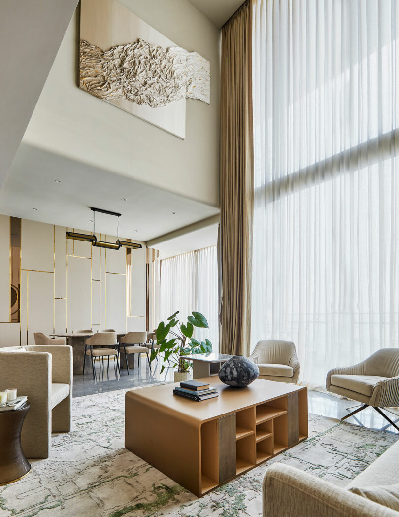 فضای داخلی اتاق نشیمن مدرن با پنجره های بزرگ، پرده های شفاف و مبلمان معاصر.