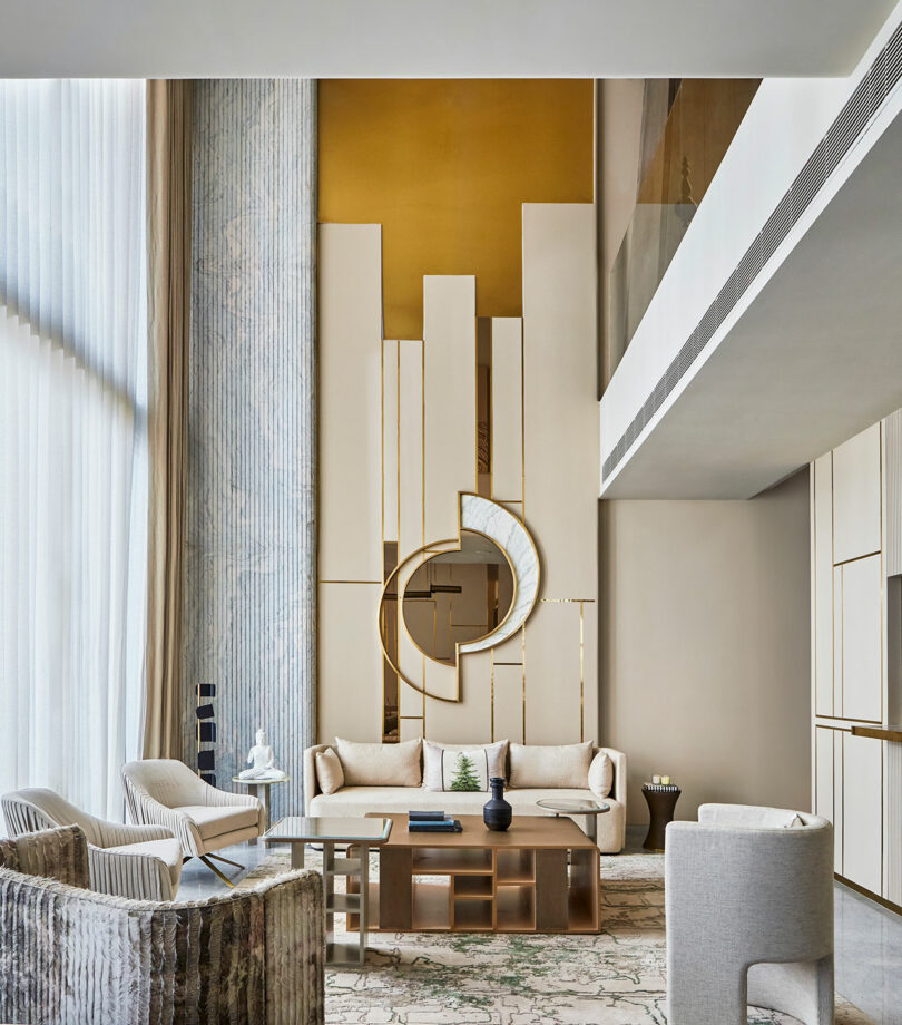 Modern living room with gold and beige tones, featuring a geometric wall design and contemporary furniture.