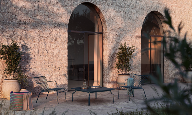 Patio at twilight with modern furniture against a textured stone wall.