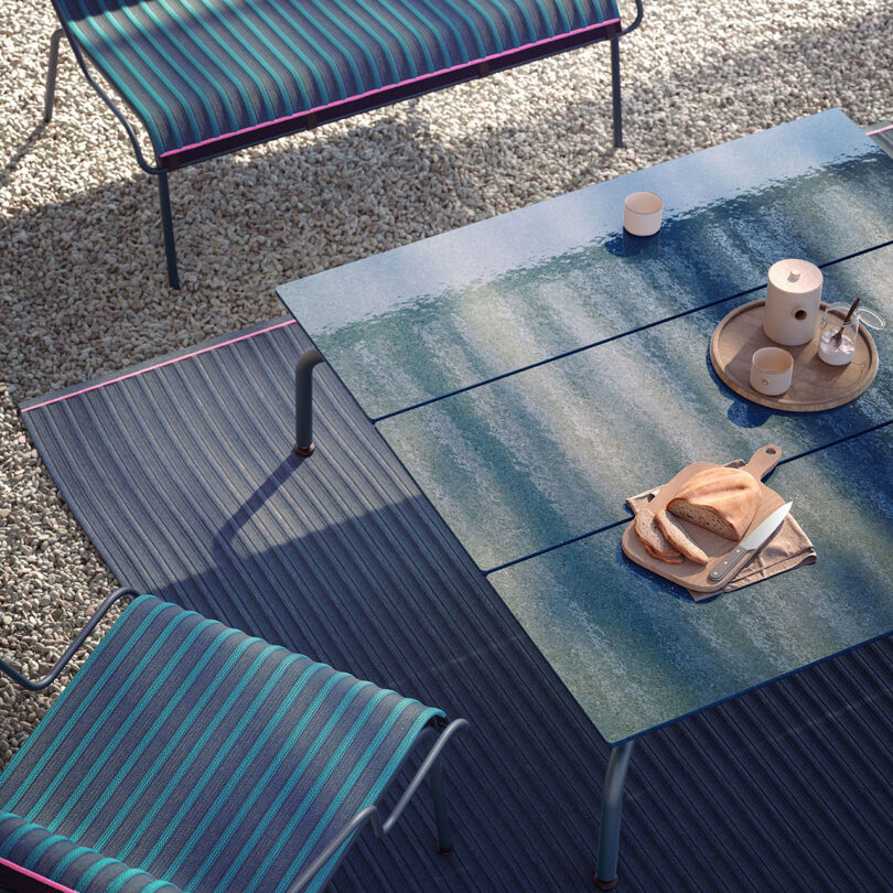 Outdoor patio setting with modern furniture and a set table under sunlight.