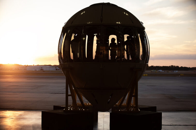 A large spherical space capsule used to take 8 passengers up onto the world’s first luxury spaceflight service, sitting on the tarmac at an airport.