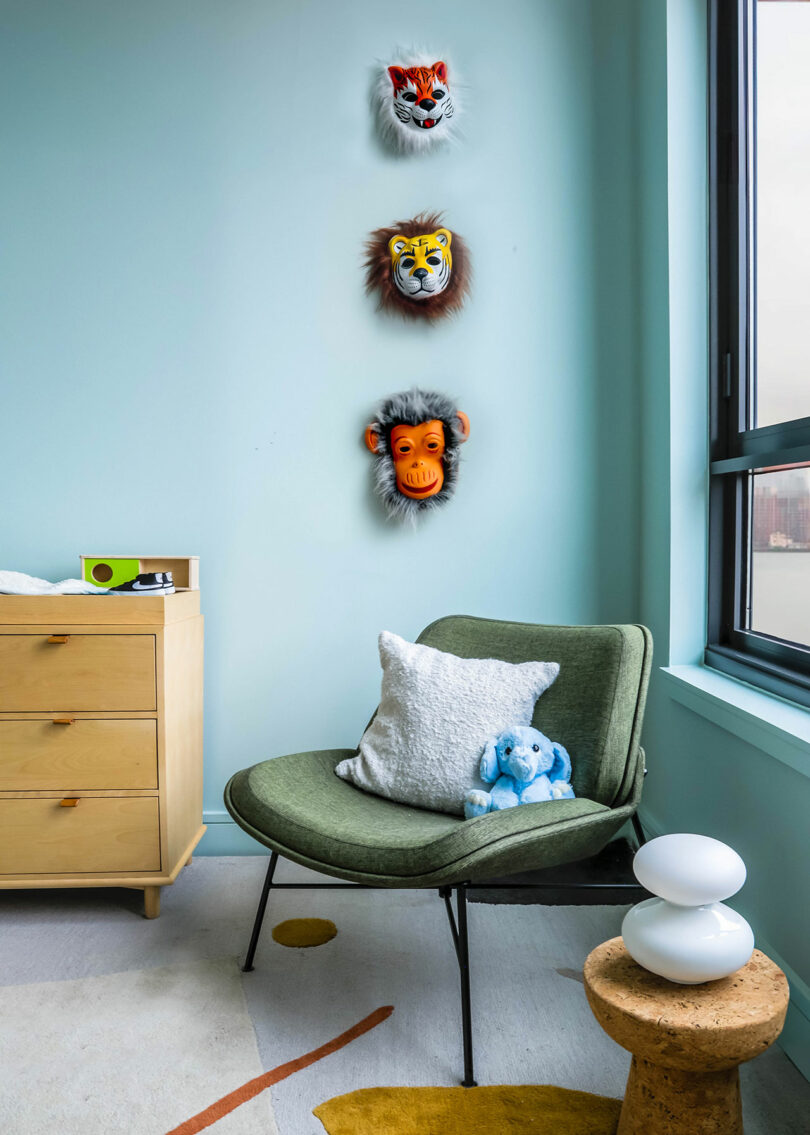 A changing table and wall art above a rocking chair in a baby's room.