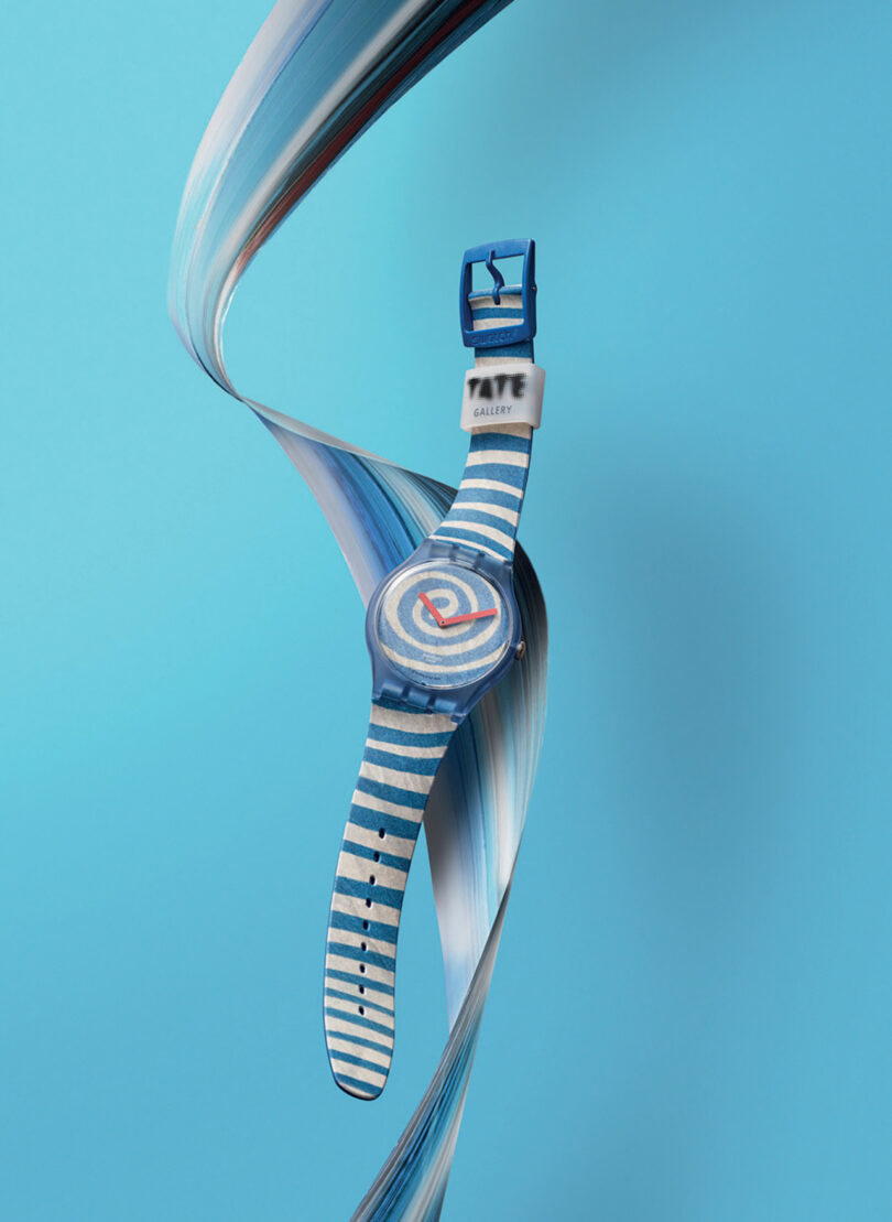 A Swatch x Tate Gallery Watch Collection piece with a striped band twisted artistically against a blue background.
