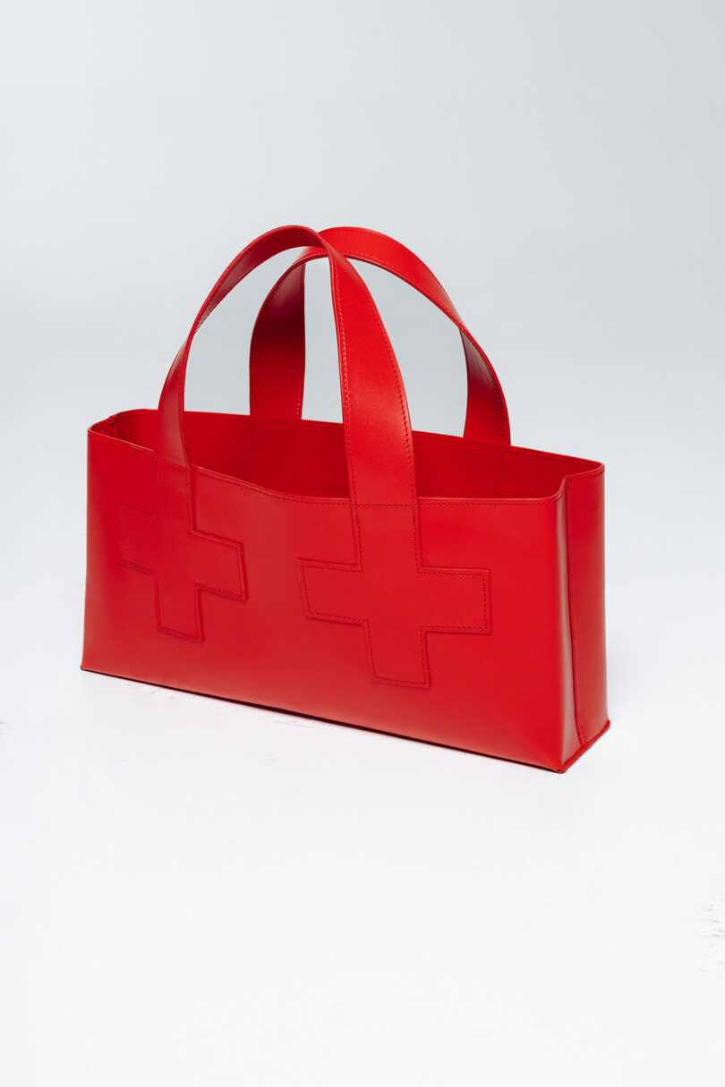 Red tote bag with cross symbols on a plain background.