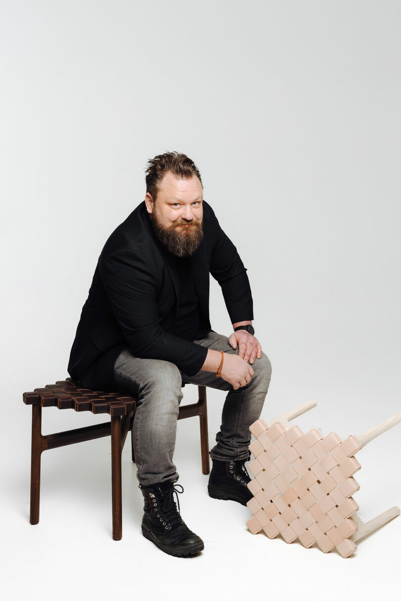 Man with a beard sitting on a small wooden bench.