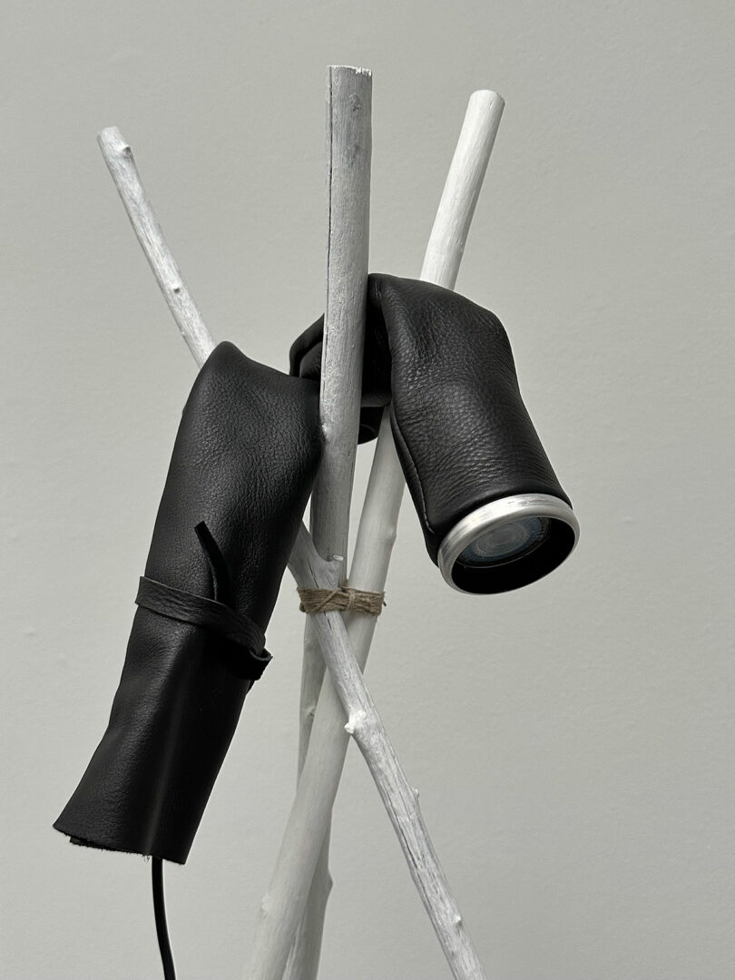 One extended, adjustable flashlight wrapped in black material, rested on white sticks against a light gray background.