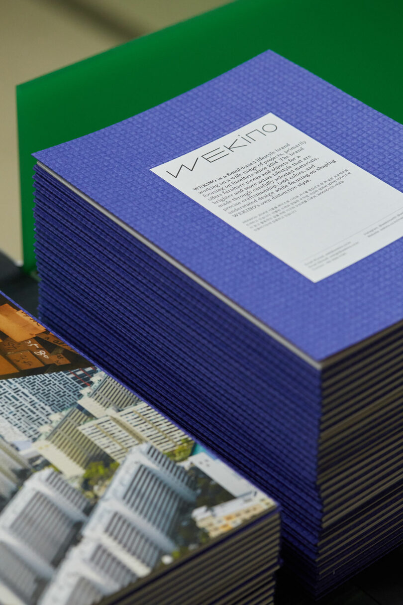 A stack of blue magazines with one titled "Wekino" on top, next to other printed materials.