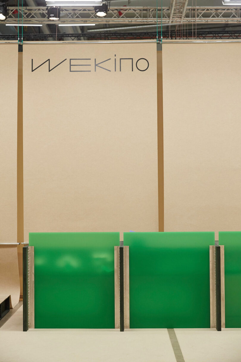 Trade show booth with the Wekino logo displayed over green partitions.