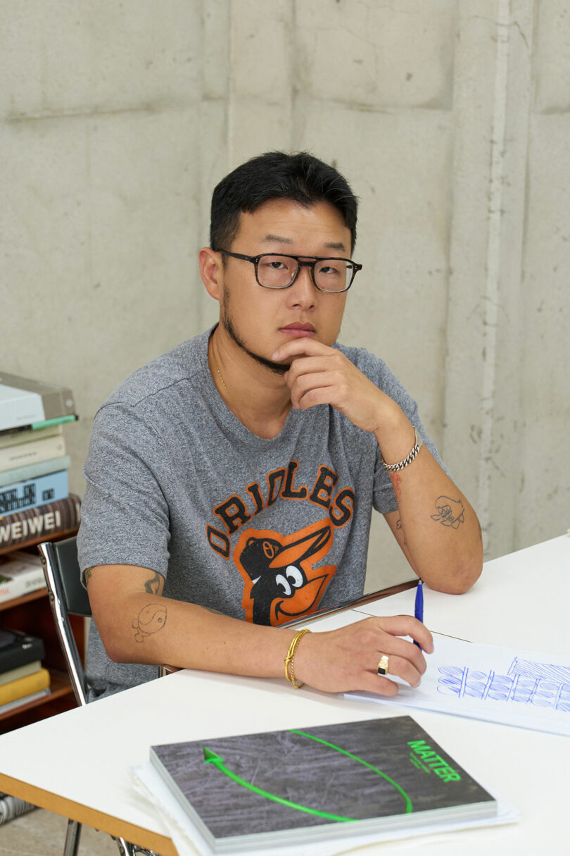 A young man with glasses sitting at his desk.