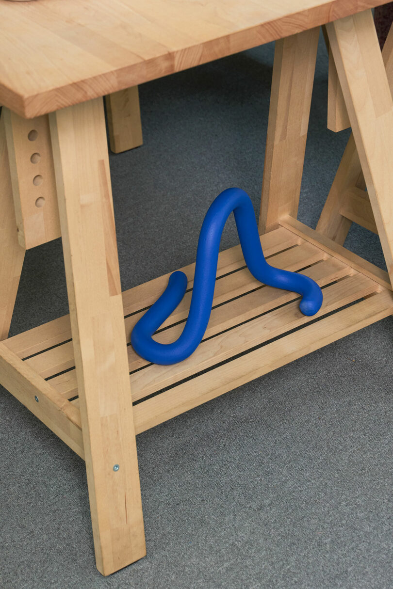 A blue flexible object placed under a wooden table.