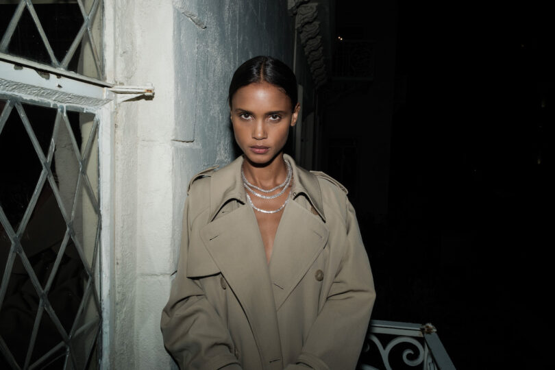 woman wearing trench coat with layers of diamond necklaces