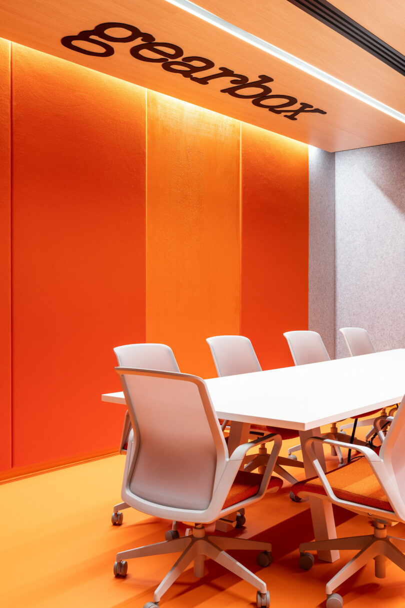 Conference room with long white conference table with orange glass and white task chairs