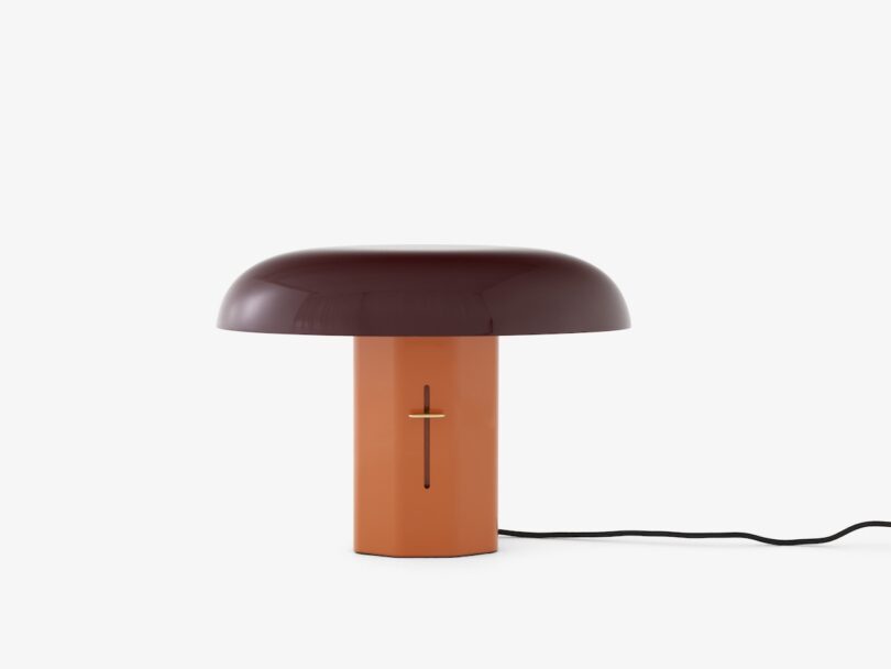 Modern table lamp with a dark red shade and orange base on a white background.