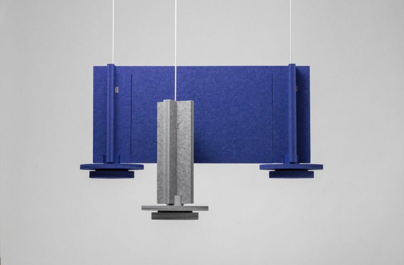 a grey felt pendant light in front of two purple felt pendant lights connected by a panel
