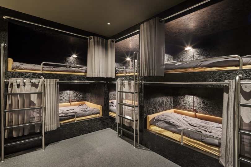 hostel dormitory-style room with metal bunk beds and individual lighting.