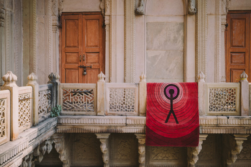 red rug with a black figure hung on balcony of a building